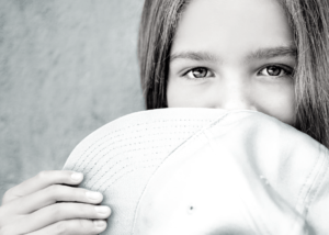 Aries Little girl smiling behind a hat ICAP Programs