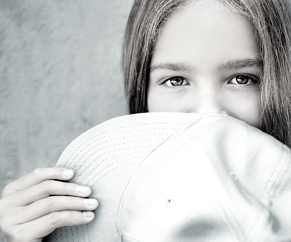 Aries Little girl smiling behind a hat ICAP Programs